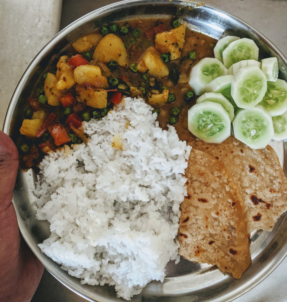 Half a chapati, alu mutter gravy, cucumber slices and some rice