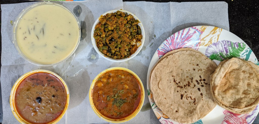 Gujarati tiffin for sundays - chhole puri, roti and beans chickpea flour curry with gujarati kadi and dal fry